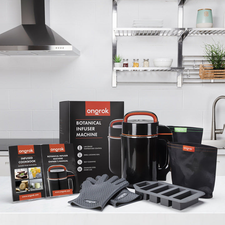 ONGROK Large Botanical Infuser Machine kit on a kitchen counter with its box, cookbook, gloves, butter mold and filter bags