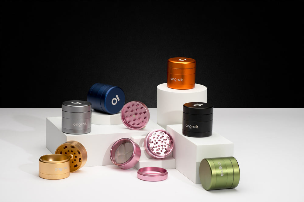 Ongrok four piece grinders in different colors from black to pink on white decorative blocks and black background