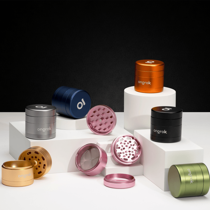 ONGROK Premium 4 Piece EZ Grinder in seven colors on white risers against black, a rose gold one taken apart