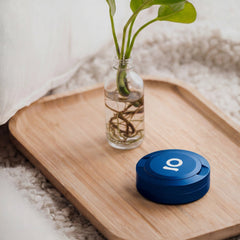 ONGROK Pouch Storage Puck in blue on a bamboo tray beside a glass vase with a plant cutting