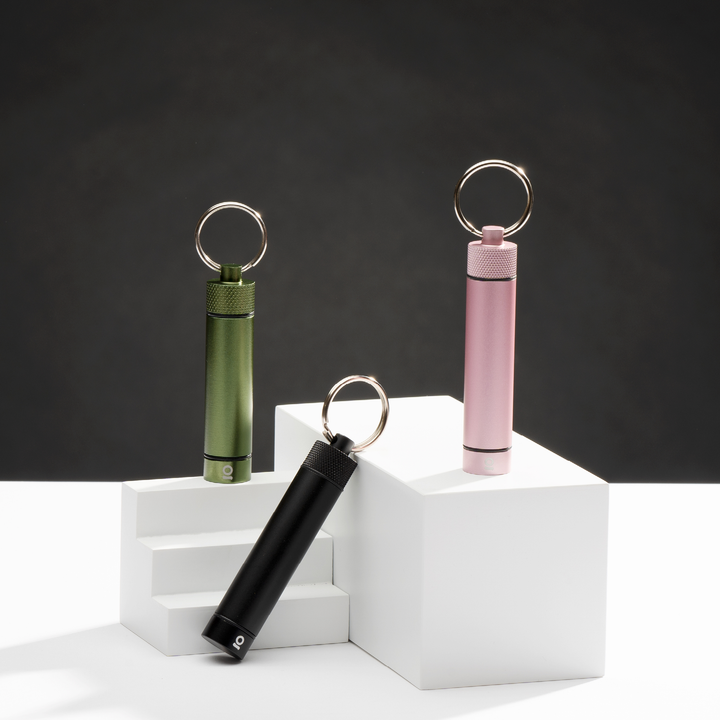 ONGROK Aluminum Storage Keychain in green, black and pink on white risers against black