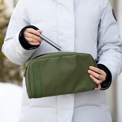 Woman in a white jacket taking a silver storage tube from a large green ONGROK Carbon-lined Wallet