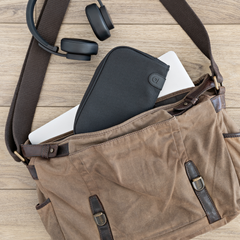 Medium black ONGROK Carbon-lined Wallet inside a canvas shoulder bag on a wooden floor