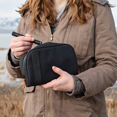 Woman outdoors holding a medium black ONGROK Carbon-lined Wallet and taking an item out